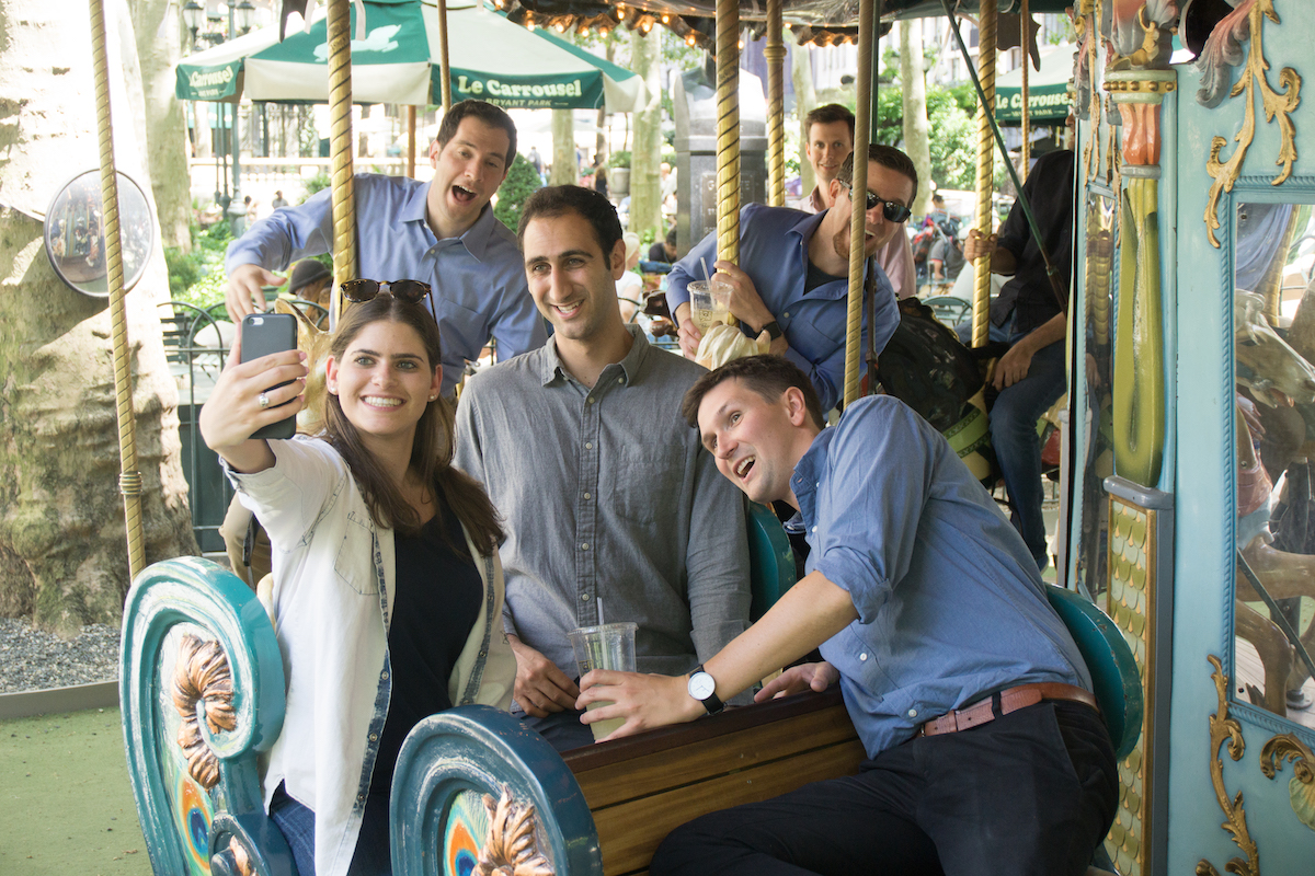 AlphaSights team members snap a selfie on a carousel