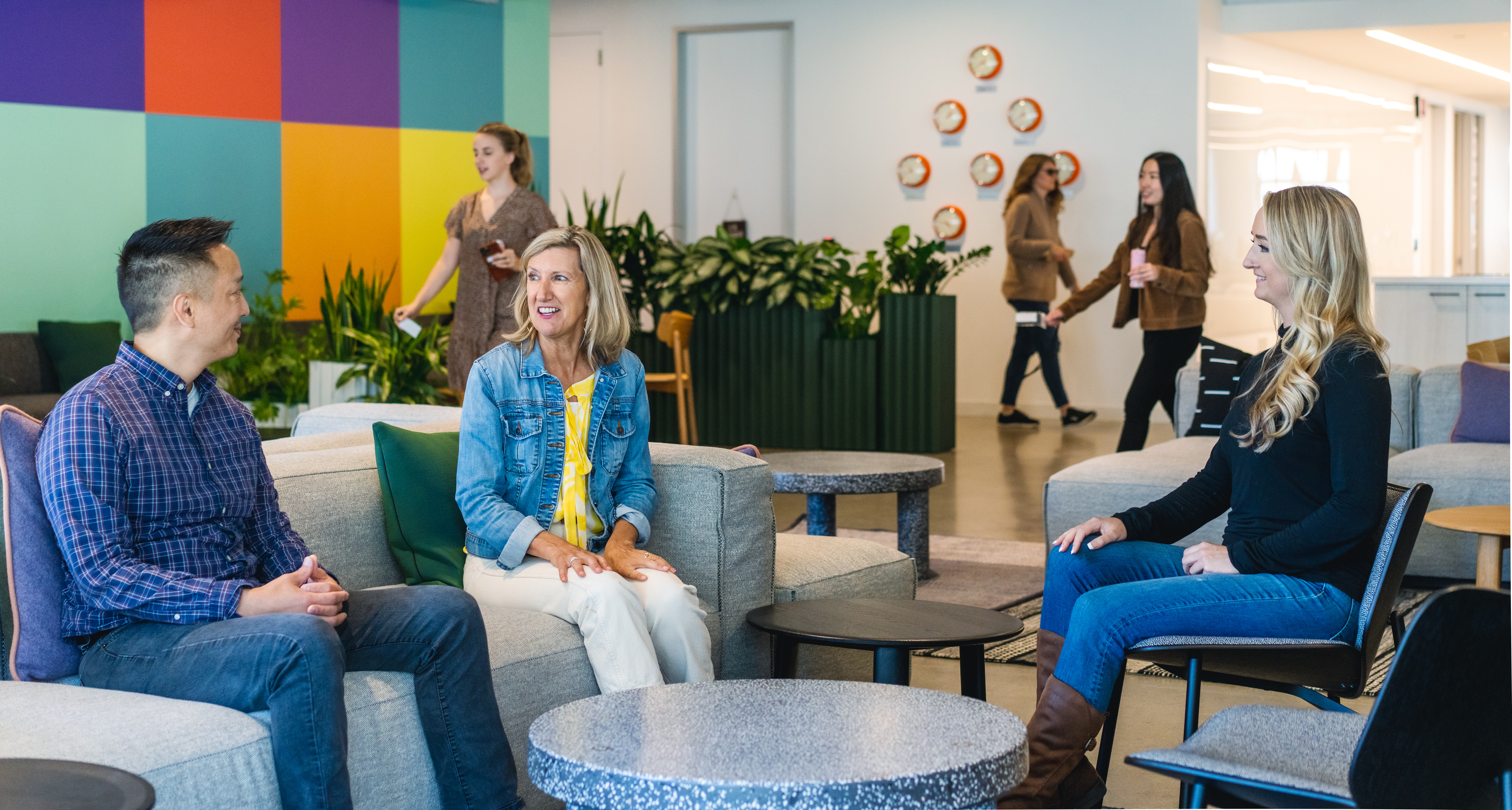 Udemy team members sitting on couches, talking and smiling