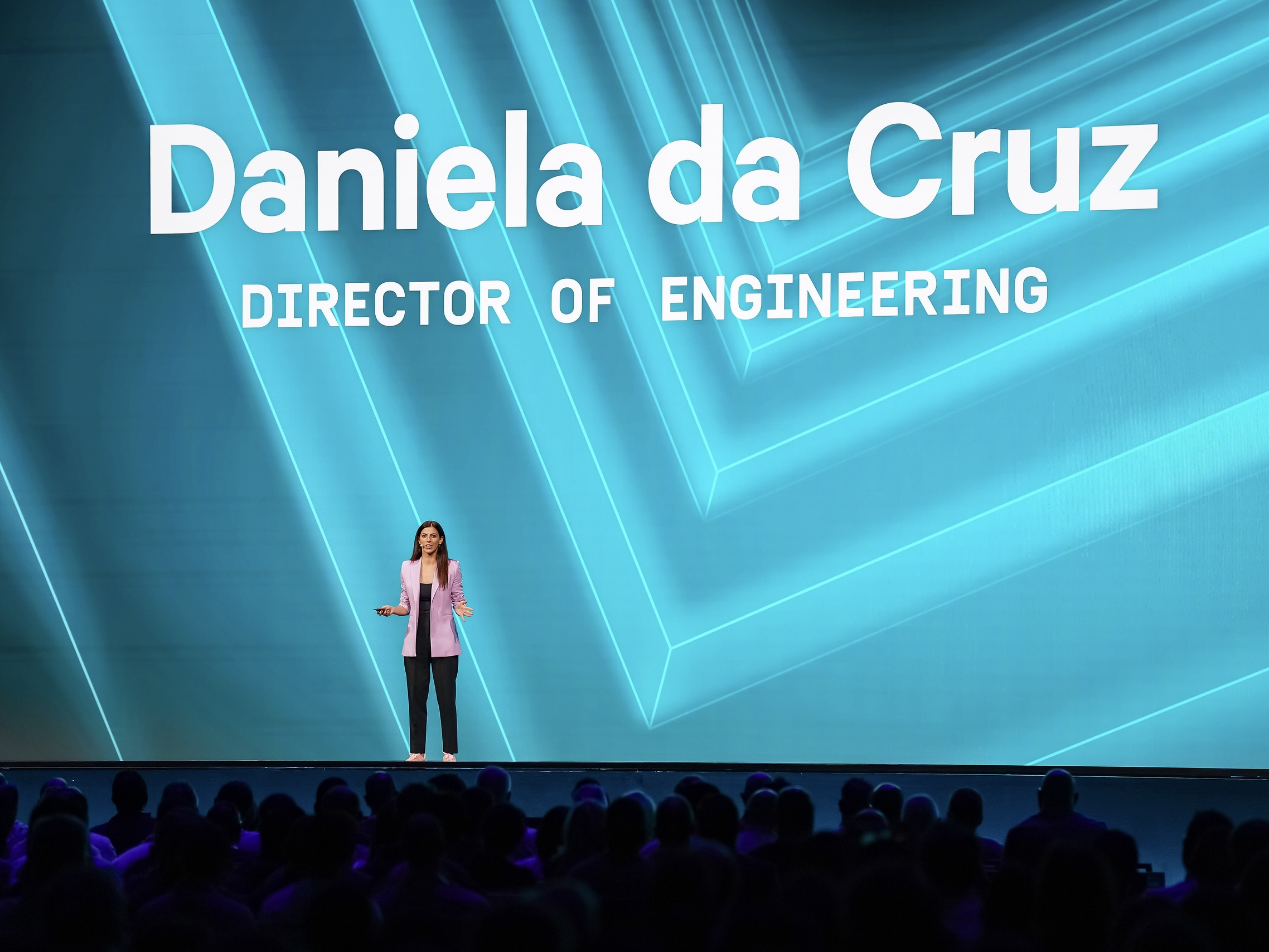  Datadog’s Director of Engineering Daniela da Cruz addresses the audience during a keynote speech with a blue-colored projection of her name and title behind her.