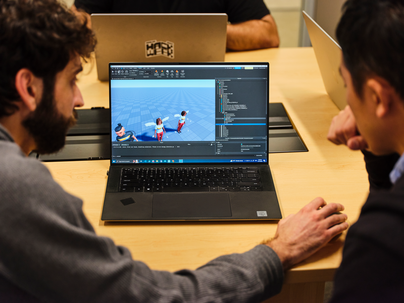 Two developers working in the Roblox platform on a laptop screen 