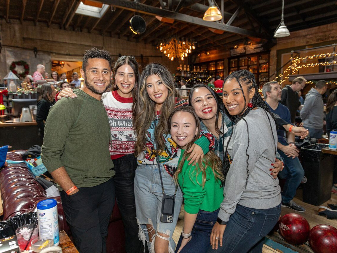 GoodRx team members smiling with arms around each other, posing for group photo at company holiday party