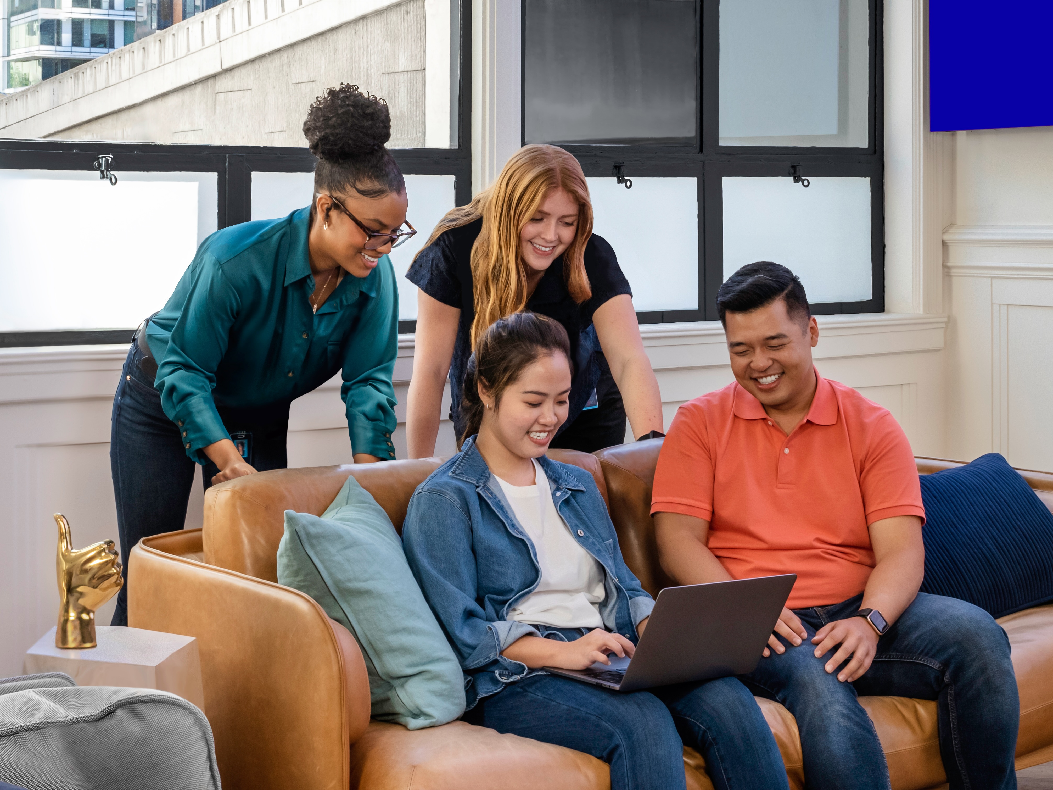 SoFi employees gather around a sofa to look at a laptop.