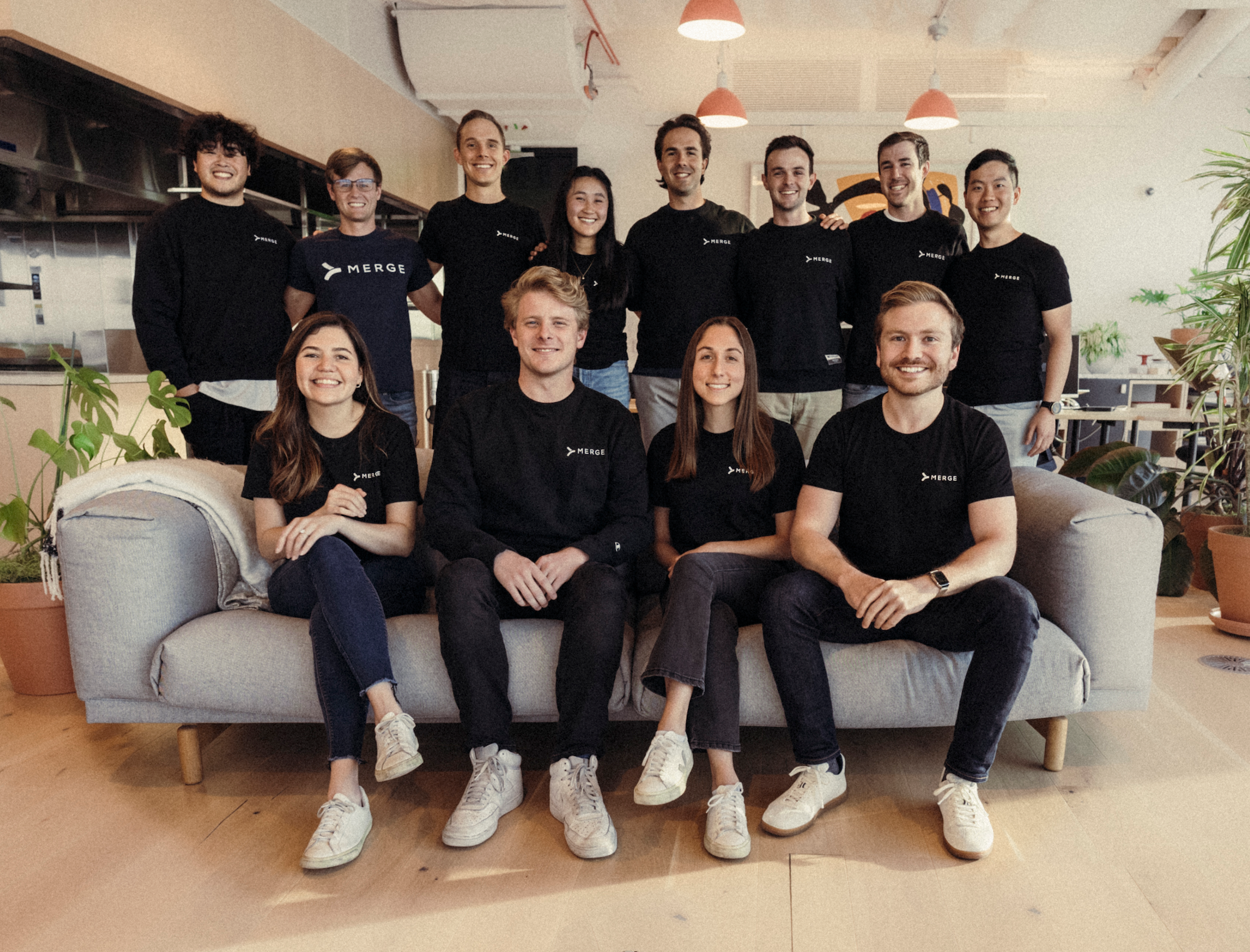 The Merge San Francisco team poses on a couch in the office for a group photo.