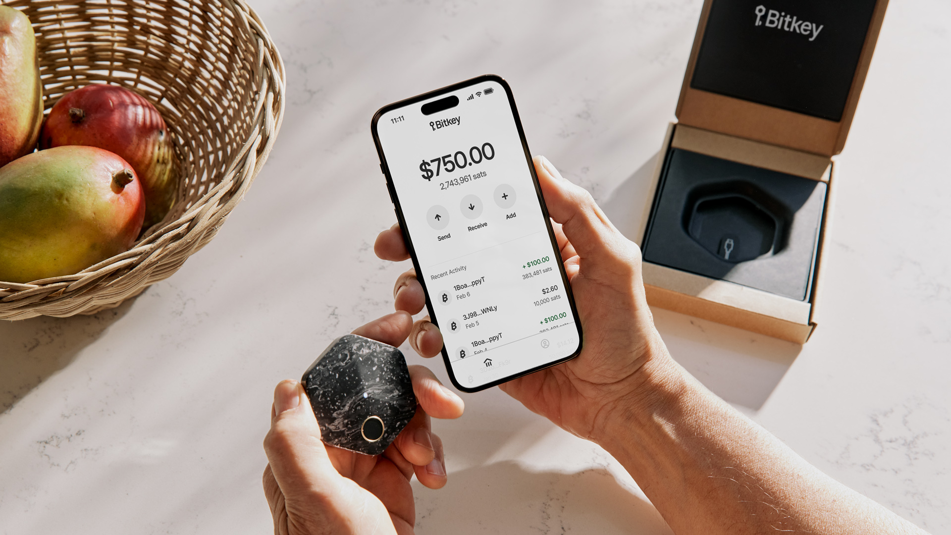 Hands holding Bitkey and viewing their bitcoin value on a phone