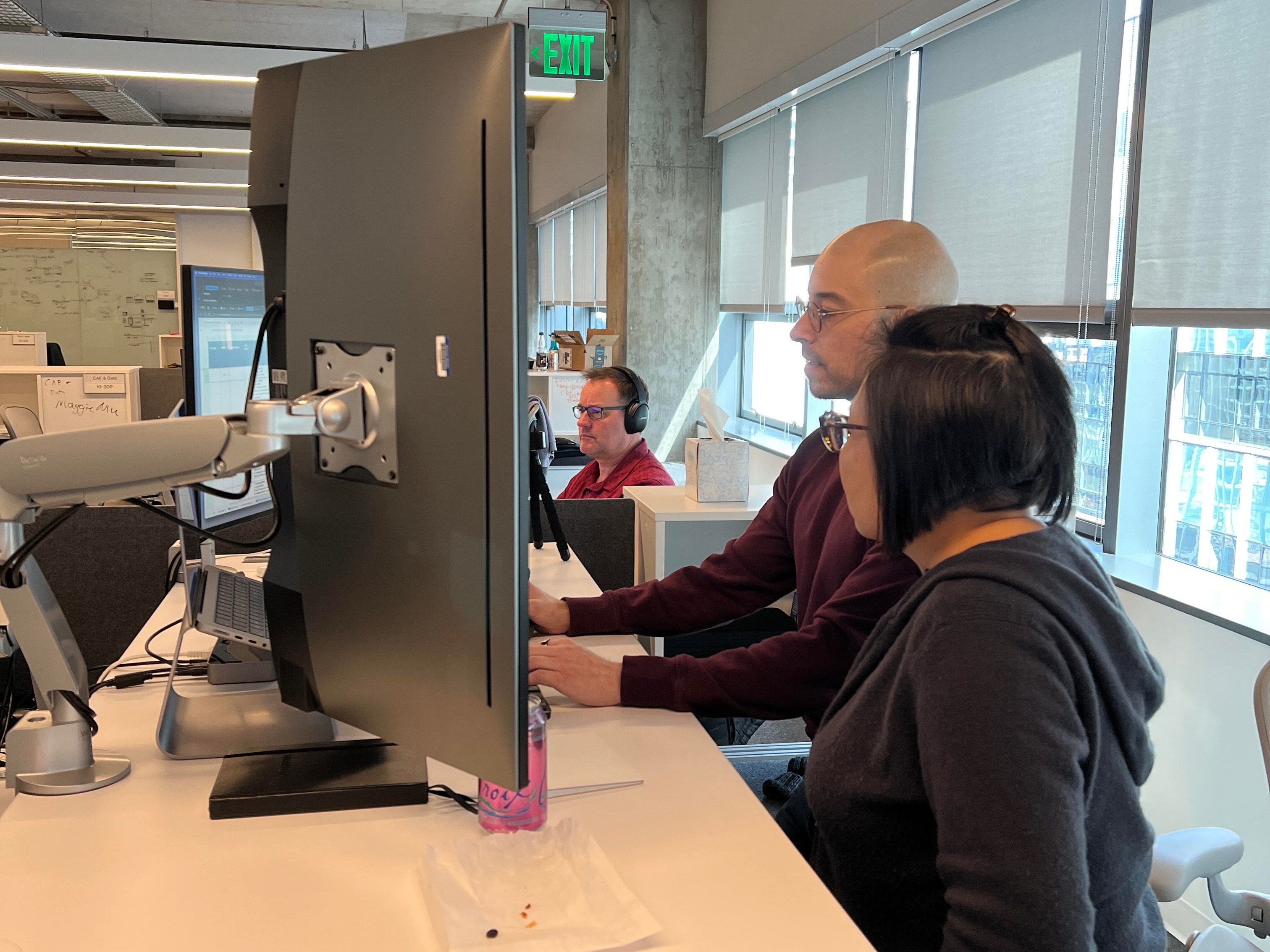 Photo of Warner Bros. Discovery employees looking at computer screen together